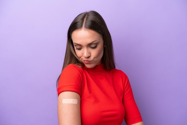 Jeune femme caucasienne portant un pansement isolé sur fond violet avec une expression triste