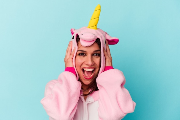 Jeune femme caucasienne portant un pyjama licorne isolé sur fond bleu