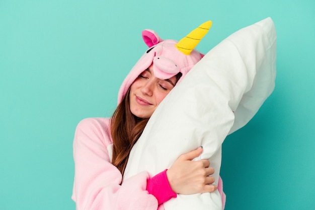 Jeune femme caucasienne portant un pyjama licorne isolé sur mur bleu