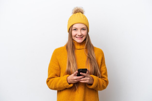 Jeune femme caucasienne portant une veste d'hiver isolée sur fond blanc en envoyant un message avec le mobile