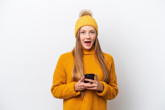 Jeune femme caucasienne portant une veste d'hiver isolée sur fond blanc surprise et envoyant un message