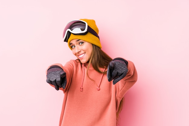 Jeune femme caucasienne portant un vêtement de ski isolé sourires joyeux pointant vers l'avant.