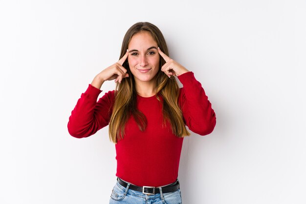 Jeune femme caucasienne posant concentré sur une tâche, gardant les index pointant la tête.