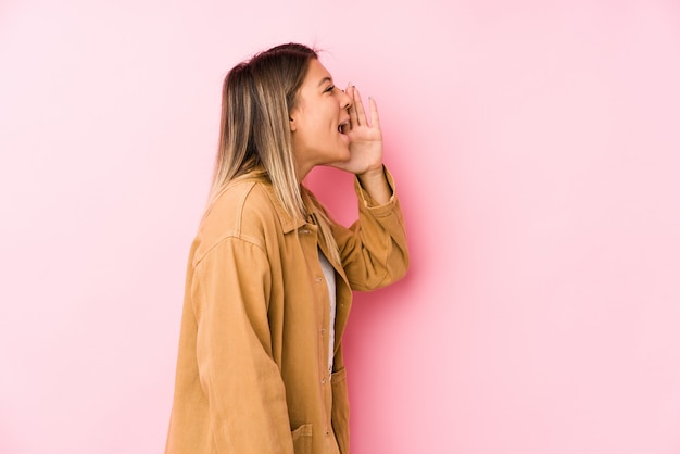 Jeune femme caucasienne posant des cris et tenant la paume près de la bouche ouverte.