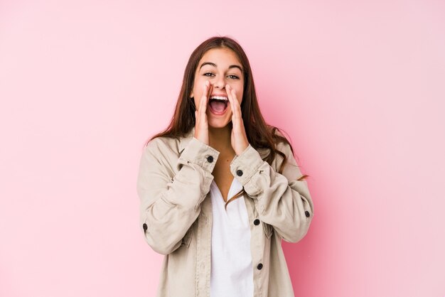 Jeune femme caucasienne posant dans une surface rose criant excité à l'avant.