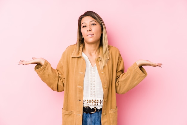 Jeune femme caucasienne posant isolé haussant les épaules confus et douteux pour tenir un espace de copie.