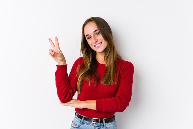 Jeune femme caucasienne posant isolé joyeux et insouciant montrant un symbole de paix avec les doigts.