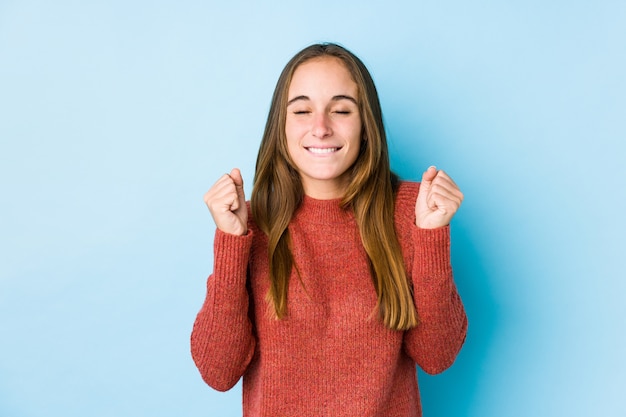 Jeune femme caucasienne posant isolé levant le poing, se sentant heureux et réussi. Concept de victoire.