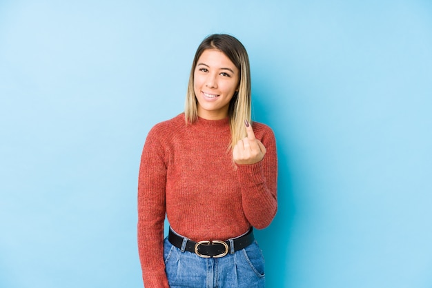 Jeune femme caucasienne posant isolé pointant avec le doigt vers vous comme si vous vous rapprochez.