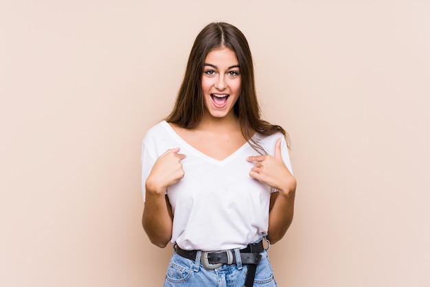 Jeune femme caucasienne posant isolé surpris pointant avec le doigt, souriant largement.