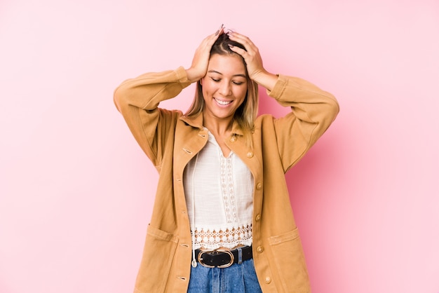 Jeune femme caucasienne posant des rires isolés gardant joyeusement les mains sur la tête. Concept de bonheur.