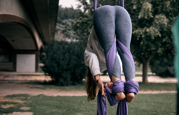 Photo une jeune femme caucasienne pratiquant une performance de soie aérienne accrochée à un pont dans une ville de parc