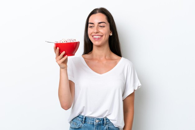 Jeune femme caucasienne prenant du lait de petit déjeuner isolé sur fond blanc avec une expression heureuse