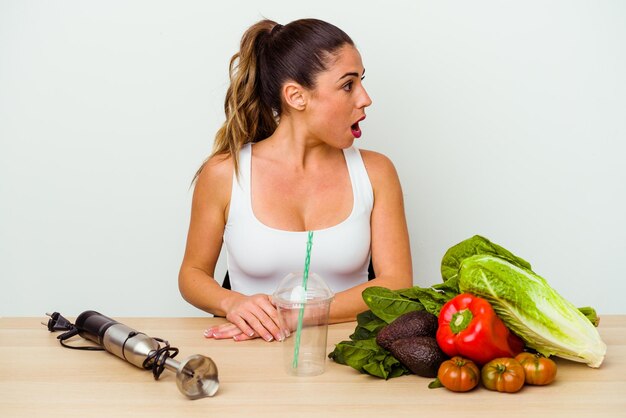 Jeune femme caucasienne préparant un smoothie sain avec des légumes