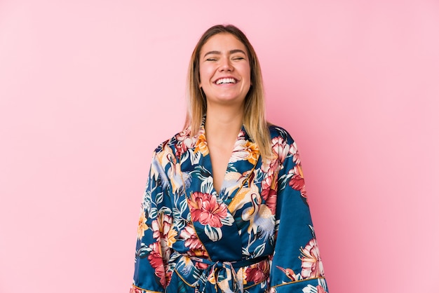 Jeune femme caucasienne en pyjama rit et ferme les yeux, se sent détendue et heureuse.