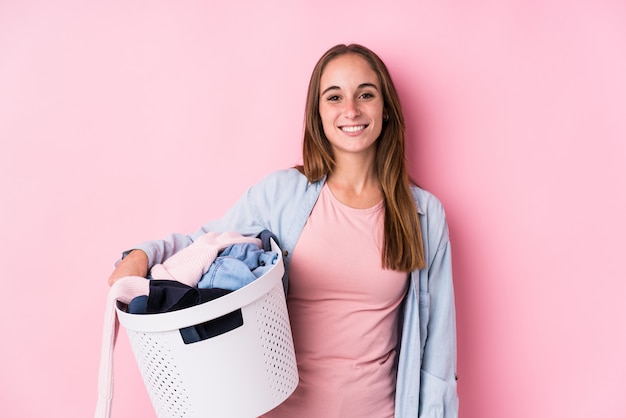 Photo jeune femme caucasienne ramasser des vêtements sales heureux, souriant et gai.