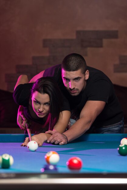 Jeune femme caucasienne recevant des conseils sur le tir à la boule de billard tout en jouant au billard