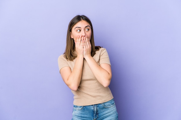 Jeune femme caucasienne réfléchie à la recherche d'un espace de copie couvrant la bouche avec la main.