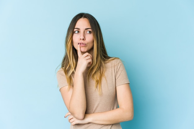 Jeune femme caucasienne regardant sur le côté avec une expression douteuse et sceptique.