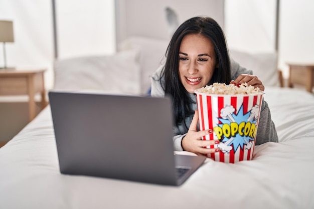 Jeune femme caucasienne regardant un film sur un ordinateur portable allongé sur le lit dans la chambre