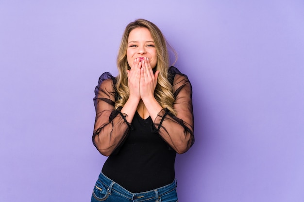 Jeune femme caucasienne riant de quelque chose, couvrant la bouche avec les mains.