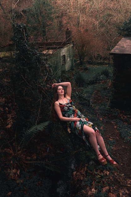 Jeune femme caucasienne avec une robe colorée au milieu de la forêt à côté d'une petite rivière