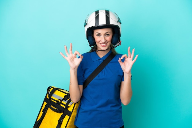 Jeune femme caucasienne avec sac à dos thermique isolé sur fond blanc montrant un signe ok avec les doigts