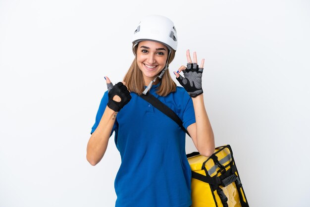 Jeune femme caucasienne avec sac à dos thermique isolé sur fond blanc montrant le signe ok et le geste du pouce vers le haut