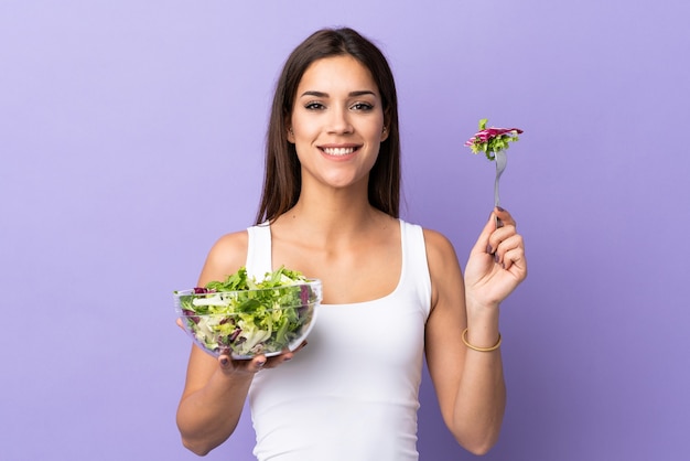 Jeune femme caucasienne avec salade sur violet