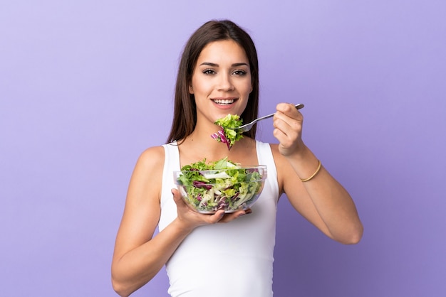 Jeune femme caucasienne avec salade sur violet