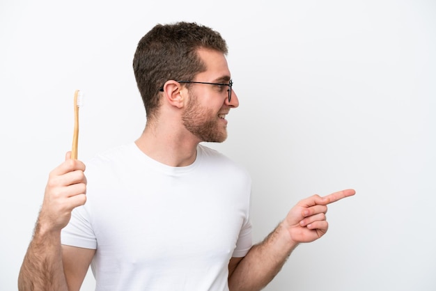 Jeune femme caucasienne se brosser les dents isolé sur fond blanc pointant vers le côté pour présenter un produit