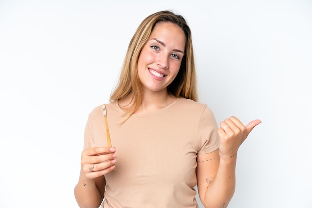 Jeune femme caucasienne se brosser les dents isolé sur fond blanc pointant vers le côté pour présenter un produit