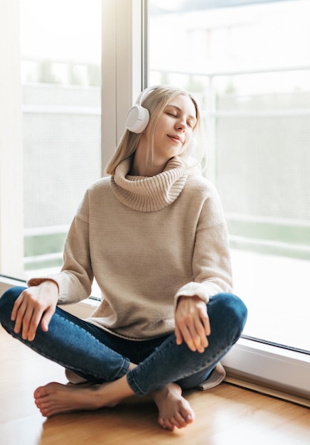 Une jeune femme caucasienne se détend à la maison avec de la musique.