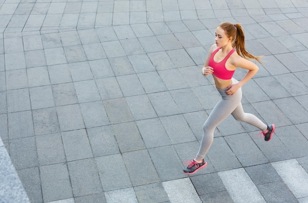 Jeune femme caucasienne sérieuse faisant du jogging en ville, espace de copie