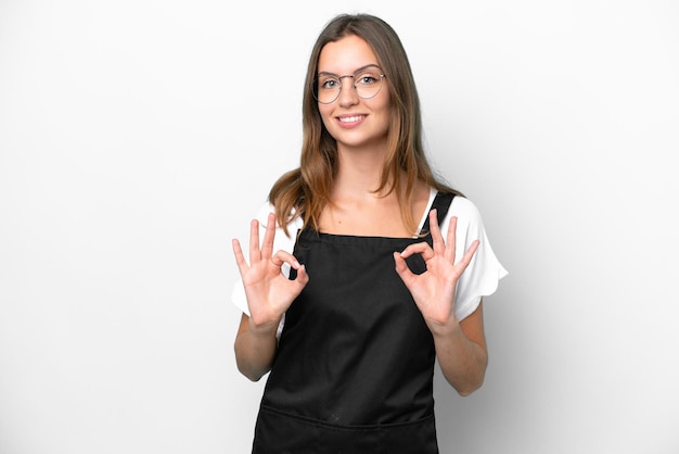 Jeune femme caucasienne de serveur de restaurant isolée sur fond blanc montrant un signe ok avec les doigts