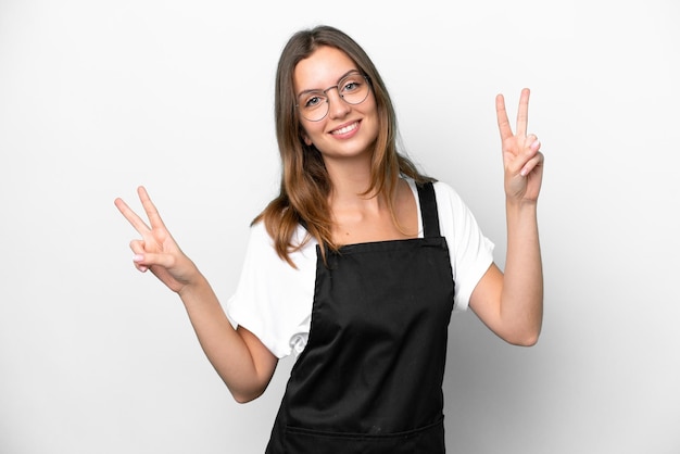 Jeune femme caucasienne de serveur de restaurant isolée sur fond blanc montrant le signe de la victoire avec les deux mains