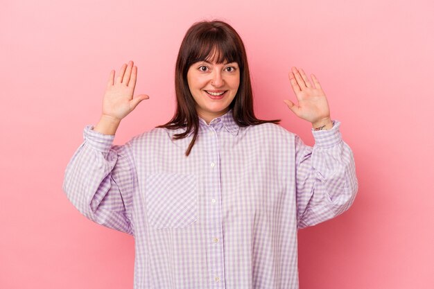 Jeune femme caucasienne sinueuse isolée sur fond rose recevant une agréable surprise, excitée et levant les mains.