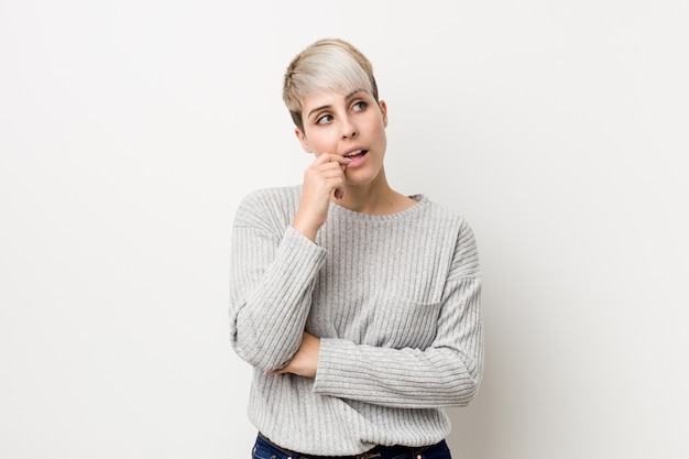 Jeune femme caucasienne sinueuse isolée sur mur blanc détendu penser à quelque chose en regardant un espace de copie.