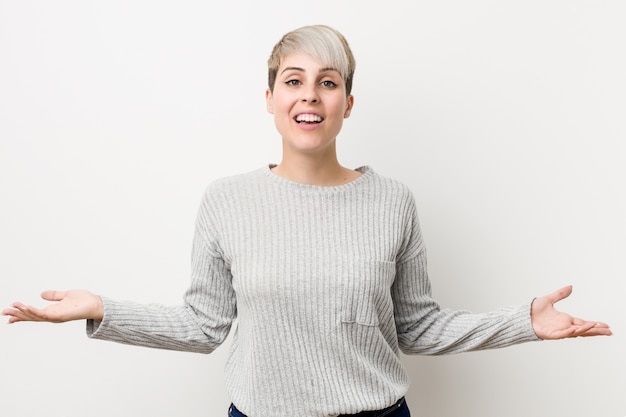 Jeune femme caucasienne sinueuse isolée sur mur blanc montrant une expression bienvenue.