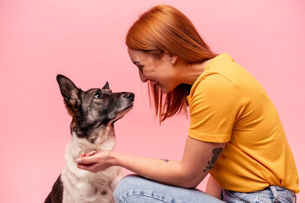 Jeune femme caucasienne avec son chien isolé sur fond rose