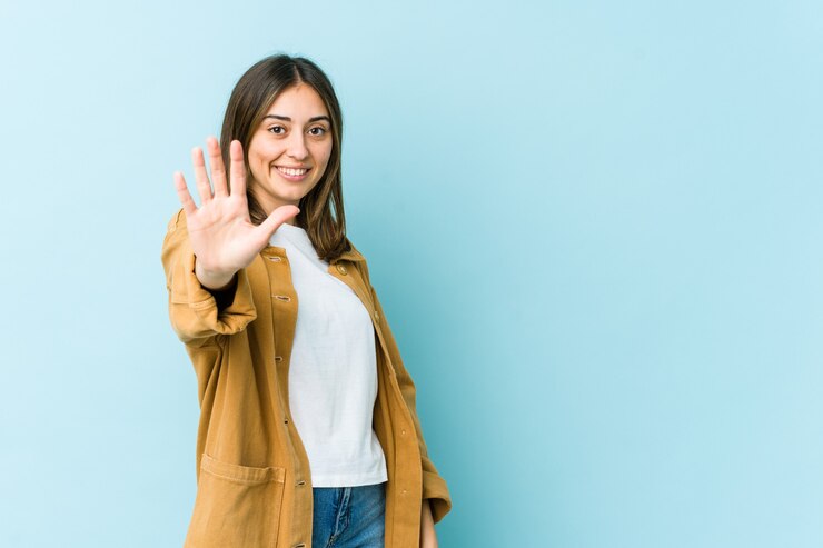 Photo jeune femme caucasienne souriante joyeuse montrant le numéro cinq avec les doigts.