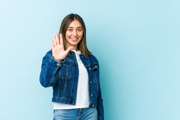 Jeune femme caucasienne souriante joyeuse montrant le numéro cinq avec les doigts.