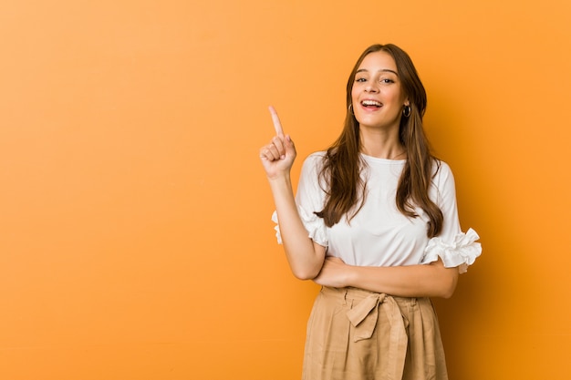 Jeune femme caucasienne souriante pointant gaiement avec l'index.