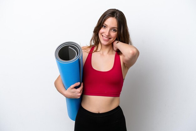 Jeune femme caucasienne sportive allant à des cours de yoga tout en tenant un tapis isolé sur fond blanc en riant