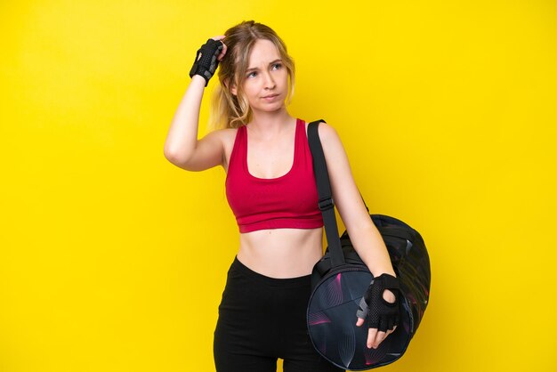 Jeune femme caucasienne sportive avec fond isolé de sac de sport ayant des doutes et avec une expression de visage confuse