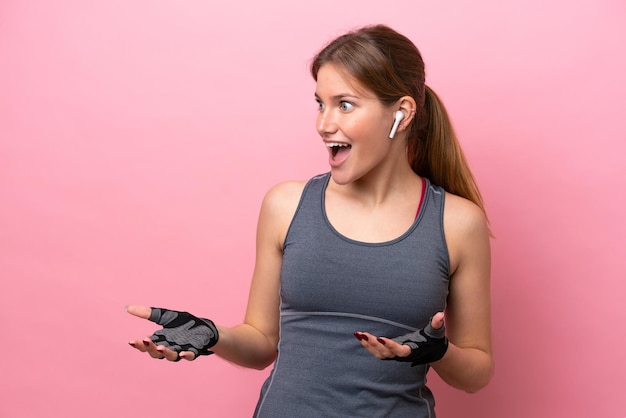 Jeune femme caucasienne sportive isolée sur fond rose avec une expression faciale surprise