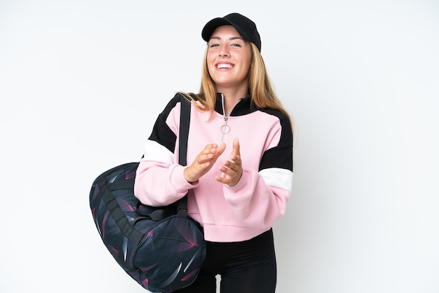 Jeune femme caucasienne sportive avec sac de sport isolé sur fond blanc applaudissant après présentation lors d'une conférence