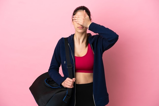 Jeune femme caucasienne sportive avec sac de sport isolé sur fond rose couvrant les yeux à la main. Je ne veux pas voir quelque chose