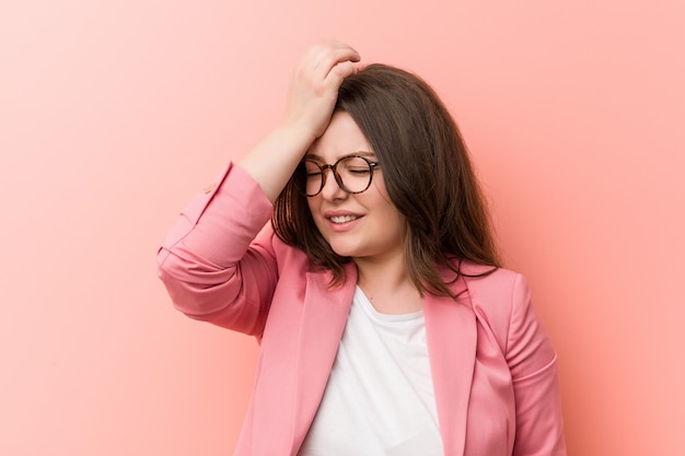 Jeune femme caucasienne de taille plus entreprise oubliant quelque chose, claquant le front avec palme et fermant les yeux.