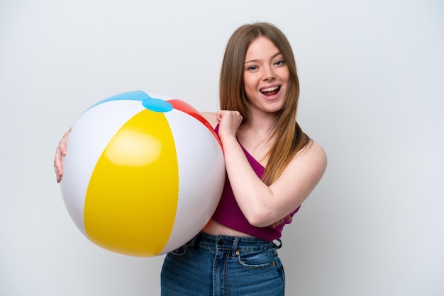 Jeune femme caucasienne tenant un ballon de plage isolé sur fond blanc célébrant une victoire